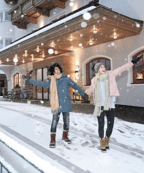 Paar im Schnee vor dem Hotel - Winterurlaub Hotel Bergzeit